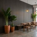 Vách lam nhựa ốp tường LS 62A màu xám đen than trang trí quán cà phê phong cách Tropical Minimalist kết hợp chậu cây terracotta lớn đèn thả đồng vintage