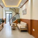 Lamri nhựa giả gỗ lam 3S39 vân cherry vàng cam ấm wainscoting tường dài vách cầu thang kính inox trần LED vàng ấm sofa gỗ sồi kệ TV gỗ sàn gạch ceramic góc perspective nhà phố Japandi Vietnamese Modern TP.HCM Xưởng Gỗ Tony