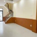 Lamri nhựa giả gỗ lam 3S39 vân cherry vàng cam ấm wainscoting phòng khách trần LED sofa gỗ sồi nệm trắng kem Japandi Vietnamese Modern nhà phố TP.HCM