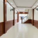 Lamri nhựa giả gỗ Nano NT18 vân walnut nâu đỏ mahogany wainscoting bọc cột hành lang vách cầu thang ốp trần tường trắng kem sàn gạch ceramic nhà phố TP.HCM