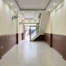 Lamri nhựa giả gỗ Nano NT29 vân walnut nâu chocolate wainscoting cả 2 bên hành lang dài vách cầu thang kính inox tường vàng kem sàn gạch ceramic nhà phố thương mại TP.HCM