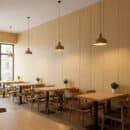 Ốp tường nhựa Nano NA215 vân gỗ sồi trắng kem sáng quán cafe nhà hàng phong cách Japandi Scandinavian đèn thả gỗ bàn ghế sồi sàn gỗ sáng cửa kính đen TP.HCM